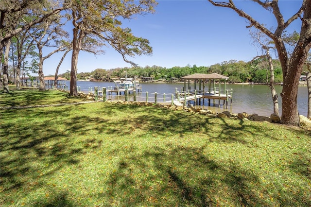 dock area featuring a water view, a lawn, and boat lift