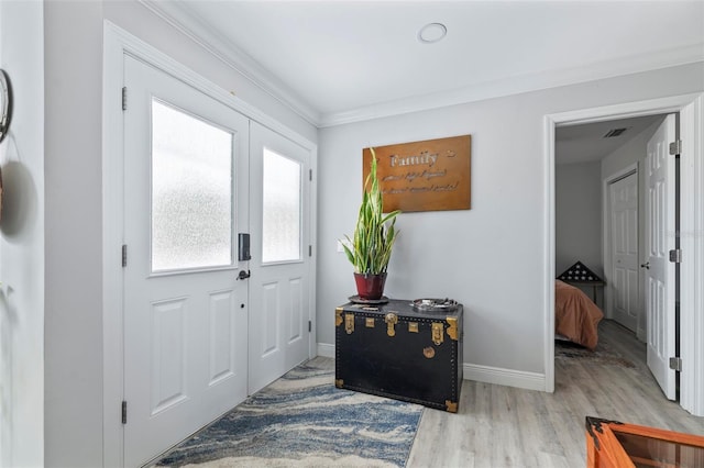 entrance foyer featuring crown molding, wood finished floors, visible vents, and baseboards