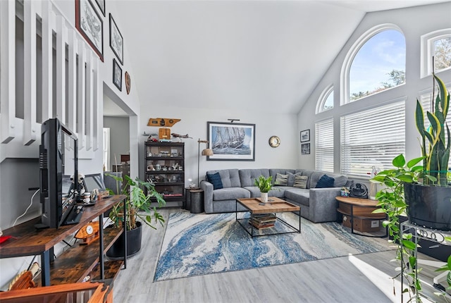 living area with high vaulted ceiling, wood finished floors, and a wealth of natural light