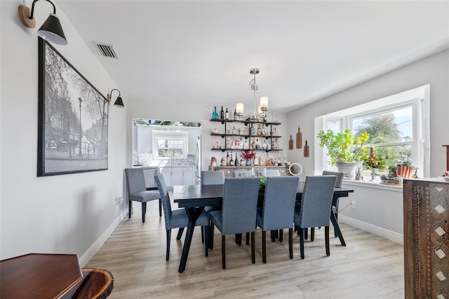 dining room featuring light wood-type flooring, baseboards, visible vents, and a chandelier