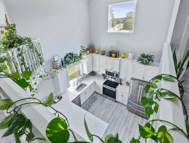 interior space featuring appliances with stainless steel finishes, plenty of natural light, white cabinets, and a sink