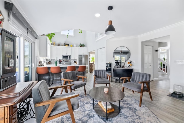 living area with light wood-style floors, baseboards, and ornamental molding