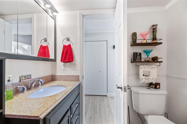 bathroom featuring a wainscoted wall, vanity, wood finished floors, and toilet