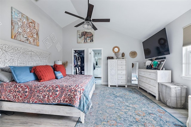 bedroom featuring lofted ceiling, ceiling fan, wood finished floors, a walk in closet, and a closet