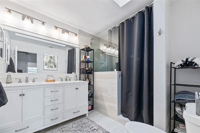 bathroom with double vanity, curtained shower, a sink, and tile walls