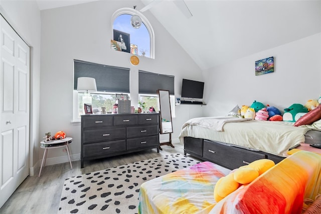 bedroom with high vaulted ceiling, multiple windows, wood finished floors, and baseboards