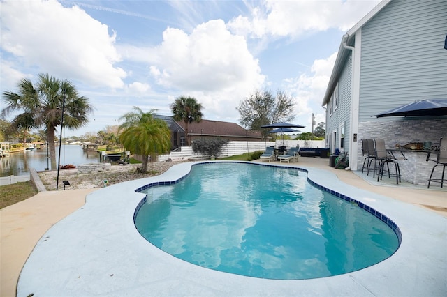 view of pool featuring a patio area, a fenced in pool, and a water view