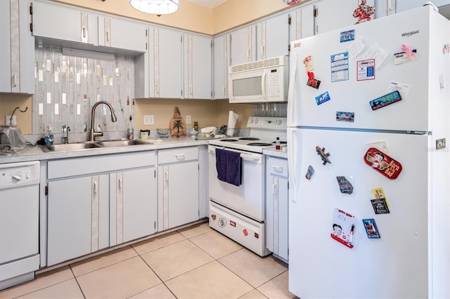 kitchen featuring light tile patterned floors, light countertops, white appliances, and a sink