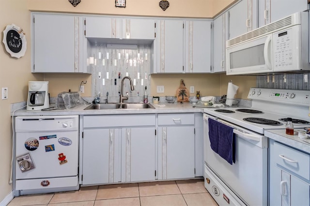 kitchen with light tile patterned floors, light countertops, white appliances, and a sink