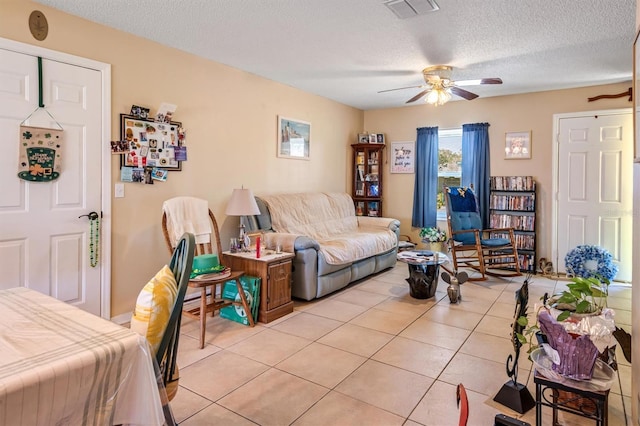 living room with light tile patterned floors, a textured ceiling, visible vents, and a ceiling fan