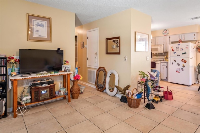 living area with light tile patterned floors, a textured ceiling, and visible vents