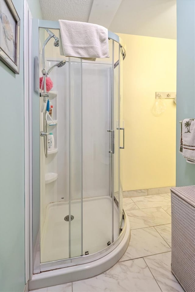 bathroom with marble finish floor, a shower stall, and baseboards