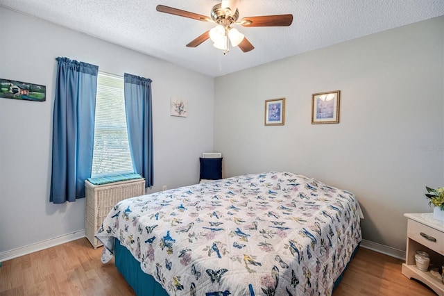 bedroom with a textured ceiling, light wood-style flooring, and baseboards