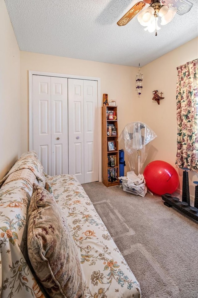 carpeted bedroom with a closet, ceiling fan, and a textured ceiling