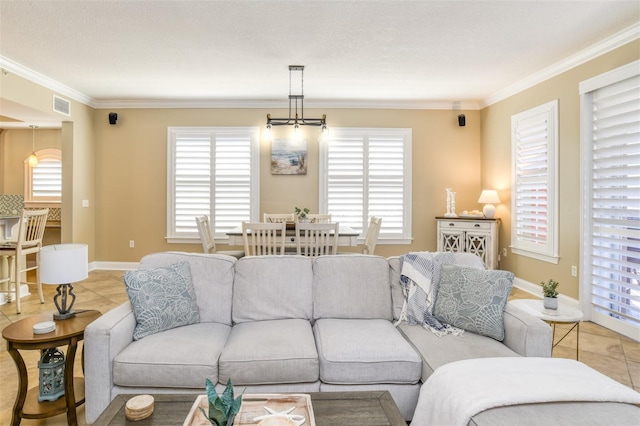 tiled living room featuring a healthy amount of sunlight, baseboards, visible vents, and crown molding