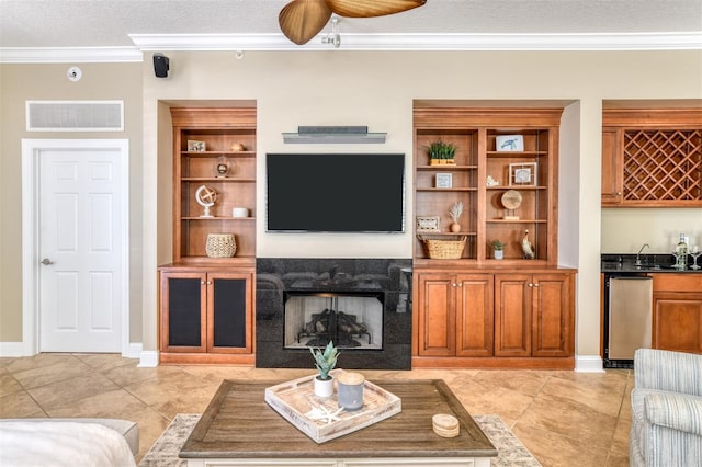 living room with visible vents, ornamental molding, a textured ceiling, indoor wet bar, and a high end fireplace