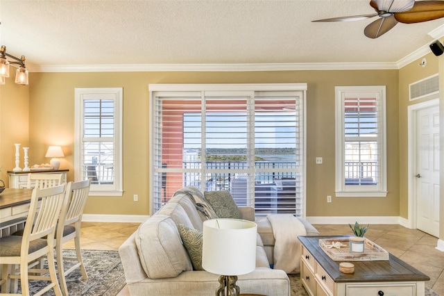 living area with light tile patterned floors, a textured ceiling, ornamental molding, and a ceiling fan