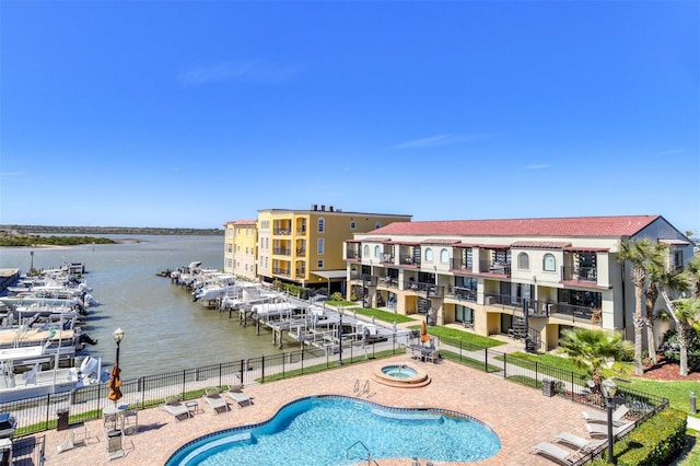 community pool featuring a water view, a patio area, and fence