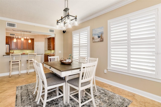 dining room with an inviting chandelier, baseboards, visible vents, and crown molding