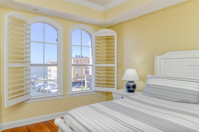 bedroom featuring ornamental molding, multiple windows, baseboards, and wood finished floors