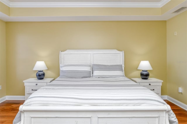 bedroom featuring visible vents, crown molding, baseboards, and wood finished floors