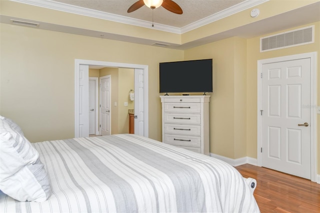 bedroom with ornamental molding, wood finished floors, visible vents, and baseboards