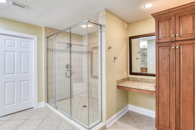 bathroom featuring a textured ceiling, visible vents, baseboards, tile patterned floors, and a stall shower