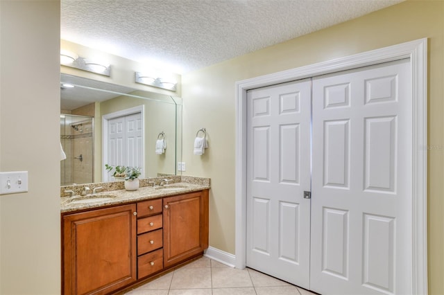 bathroom featuring tile patterned flooring, a sink, a shower stall, and a textured ceiling