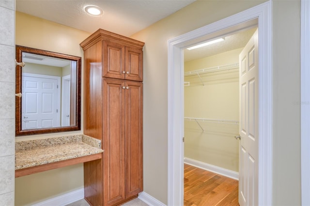 interior space featuring a spacious closet, baseboards, and wood finished floors