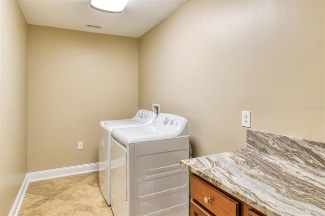 laundry area featuring washing machine and clothes dryer, light tile patterned floors, visible vents, cabinet space, and baseboards