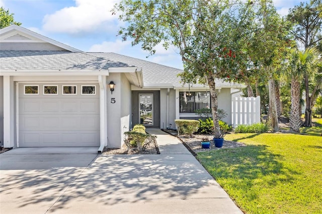 single story home with a front yard, an attached garage, concrete driveway, and a shingled roof