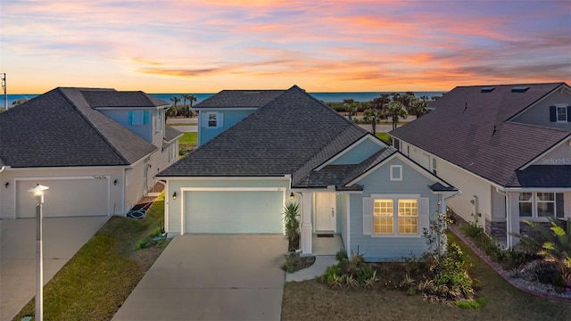 view of front of house with a garage, concrete driveway, and a shingled roof