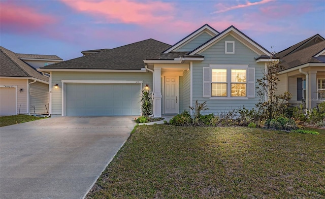 view of front facade with a lawn, concrete driveway, a garage, and roof with shingles