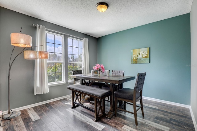 dining room featuring a textured ceiling, baseboards, and wood finished floors