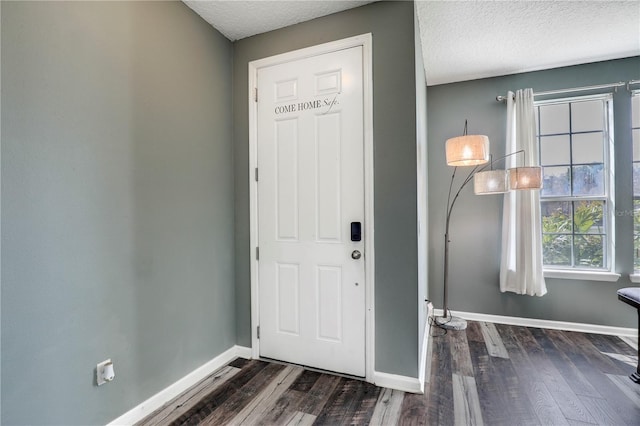 entryway with dark wood-style floors, a textured ceiling, and baseboards