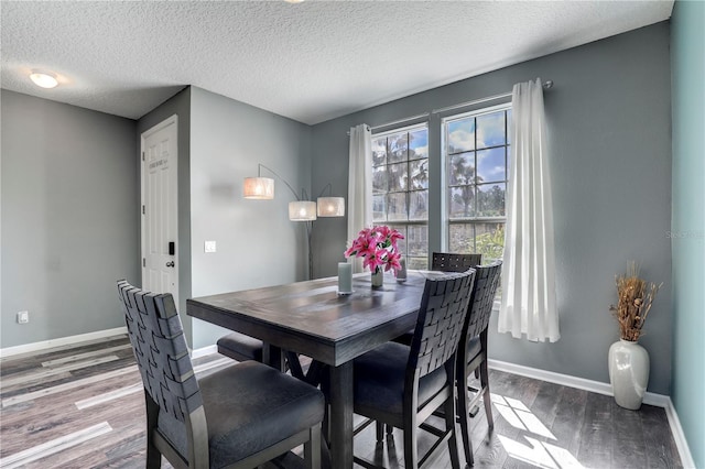 dining area with a textured ceiling, baseboards, and wood finished floors