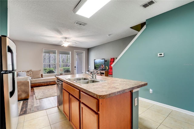 kitchen with visible vents, freestanding refrigerator, open floor plan, light tile patterned flooring, and a sink