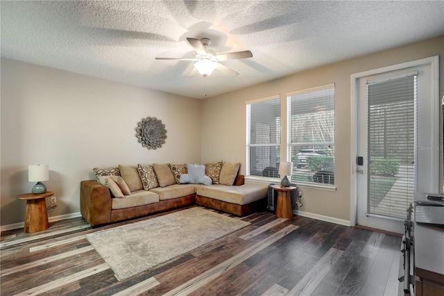 living area featuring ceiling fan, dark wood-type flooring, a textured ceiling, and baseboards