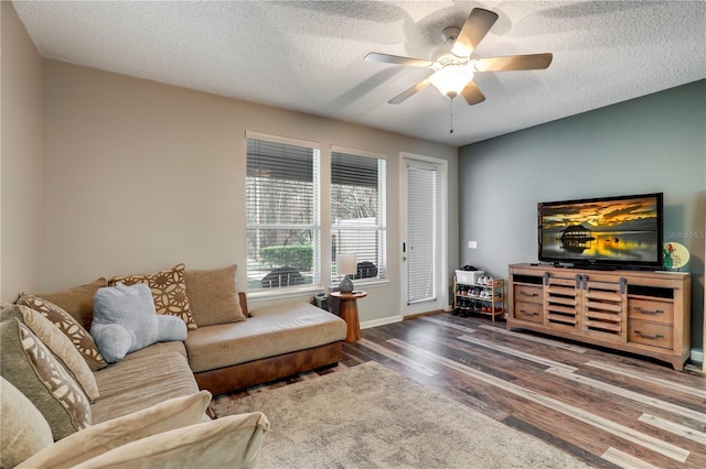 living area featuring ceiling fan, a textured ceiling, baseboards, and wood finished floors