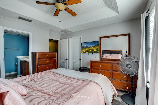 bedroom featuring visible vents, a raised ceiling, and a textured ceiling