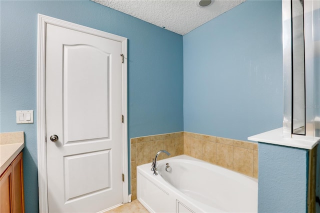 full bath featuring a textured ceiling, a garden tub, and vanity