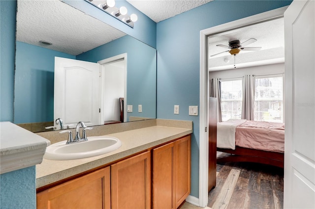 bathroom featuring connected bathroom, ceiling fan, wood finished floors, a textured ceiling, and vanity