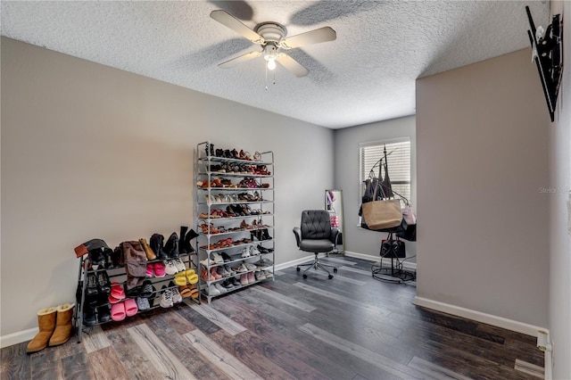 interior space featuring a textured ceiling, ceiling fan, wood finished floors, and baseboards