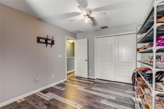 interior space featuring baseboards, visible vents, wood finished floors, a textured ceiling, and a closet