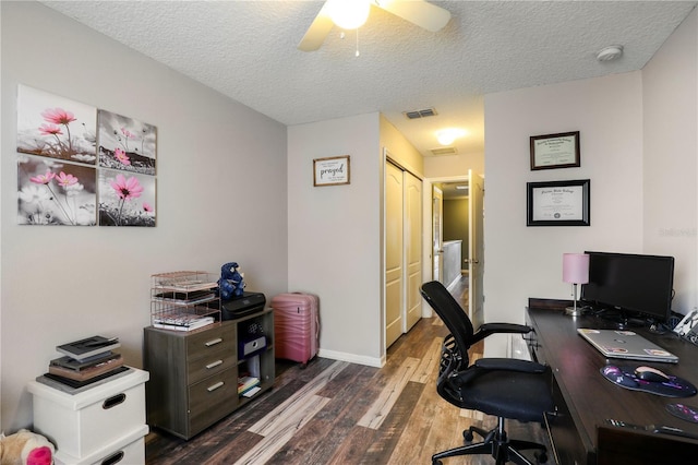 home office featuring a textured ceiling, dark wood finished floors, visible vents, and a ceiling fan