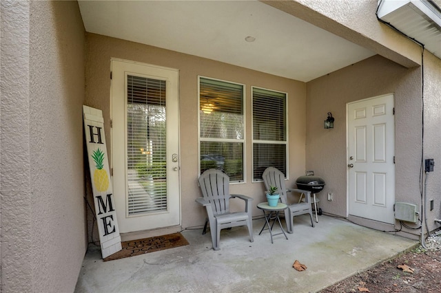 view of exterior entry with a patio and stucco siding