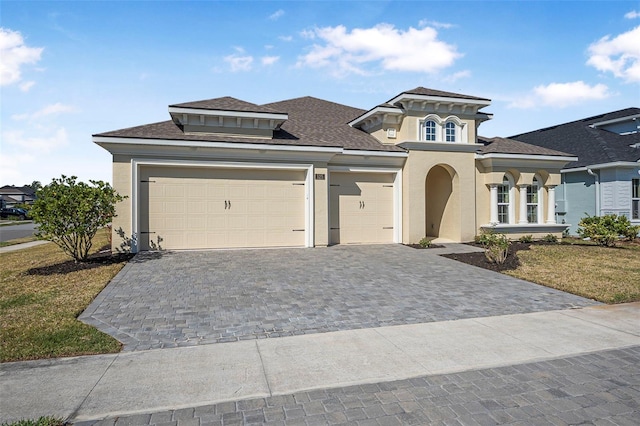 view of front facade with decorative driveway, a garage, and stucco siding