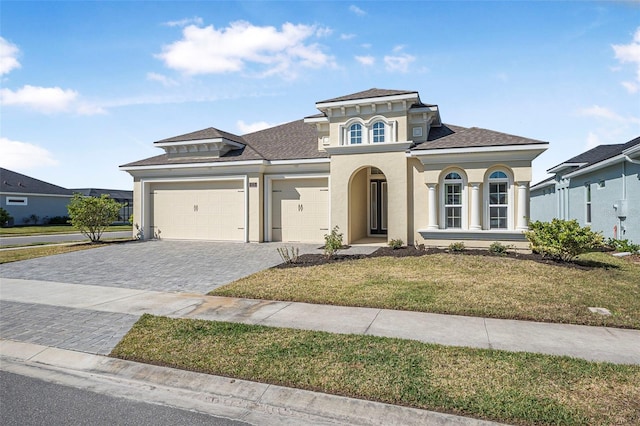 mediterranean / spanish-style house featuring decorative driveway, a front lawn, an attached garage, and stucco siding