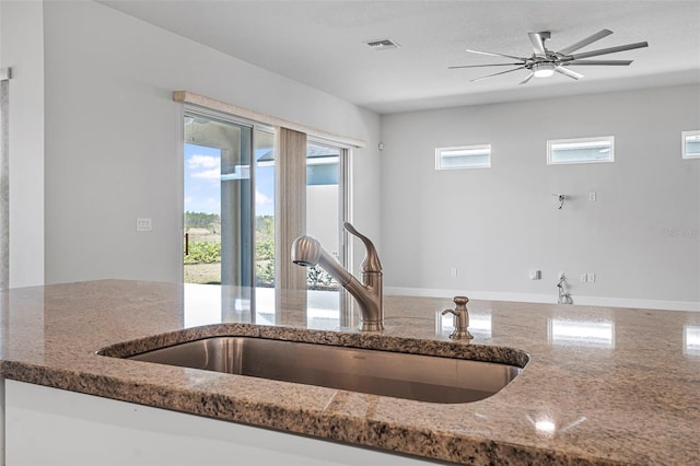 kitchen featuring ceiling fan, visible vents, stone counters, and a sink