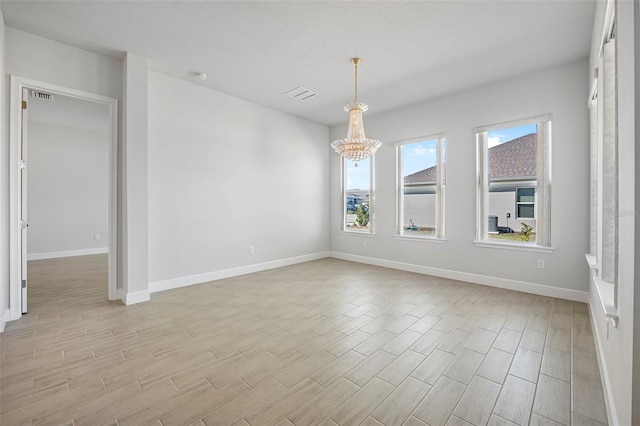 unfurnished room featuring a chandelier, visible vents, light wood-type flooring, and baseboards